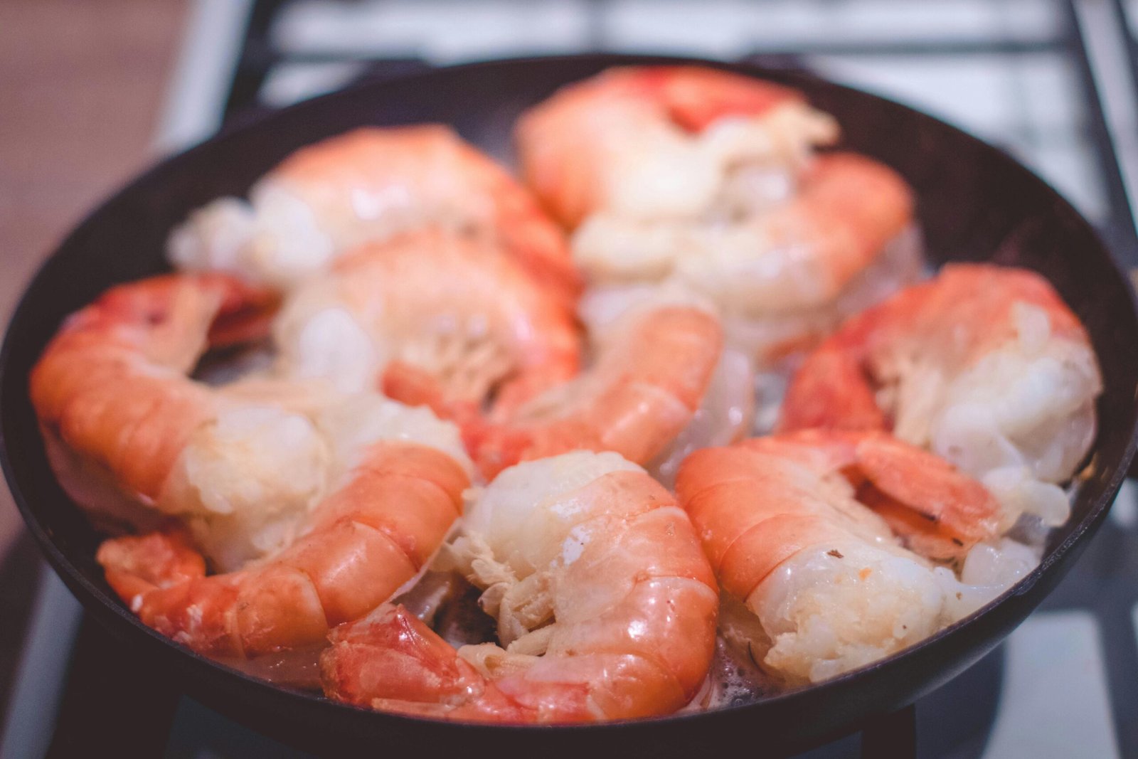 Delicious close-up of prawns sizzling in a frying pan, perfect for seafood lovers.